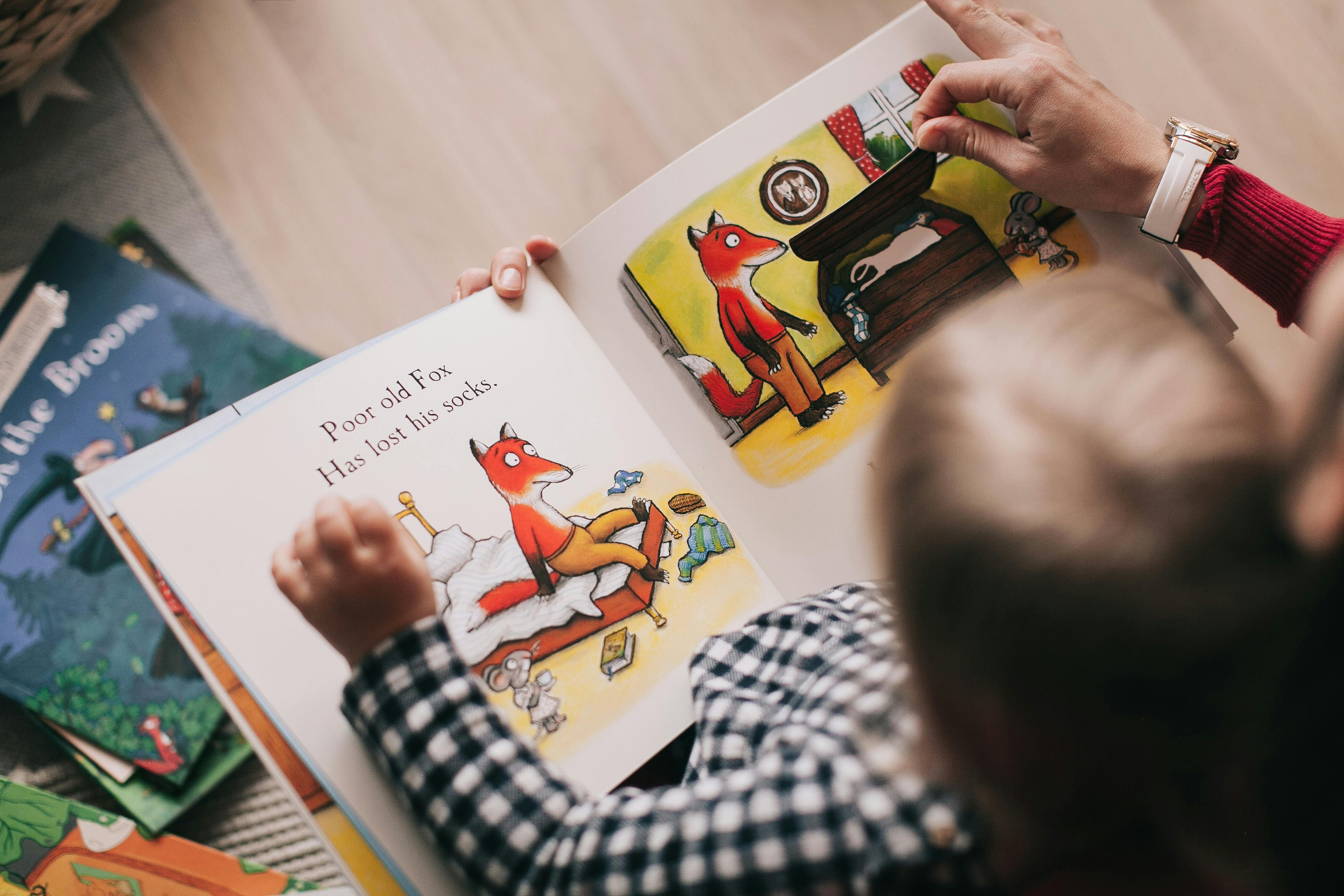 A child reading a book about a cartoon fox. 