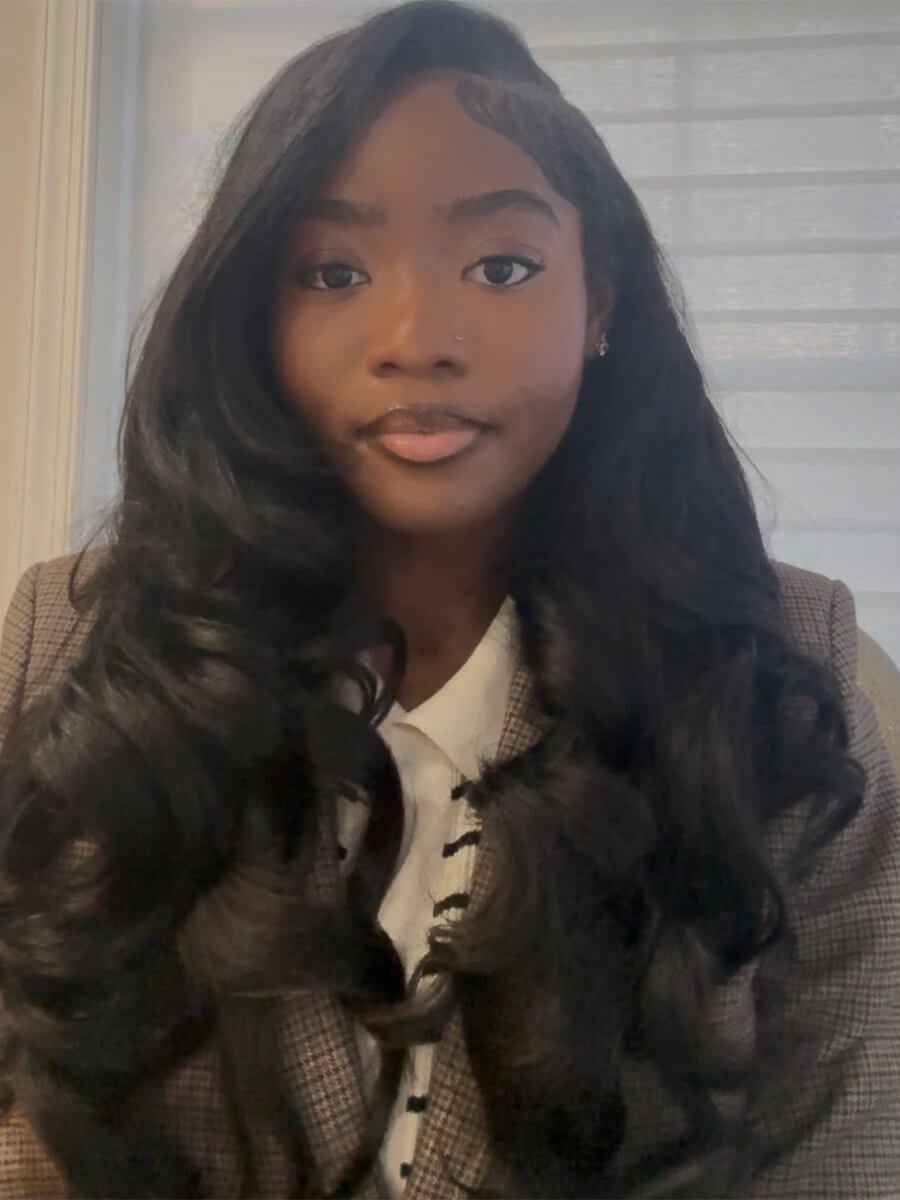 Sharon Ogunseye's headshot is her with long black hair looking straight ahead in a grey suit.