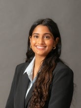 Mahika Verdire's headshot features her in a suit jacket with a gray background.