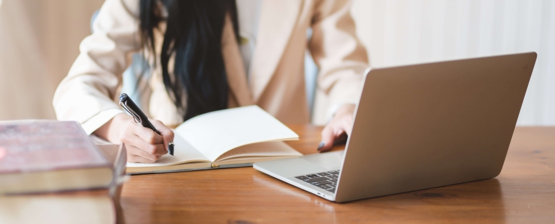 person using laptop and taking notes