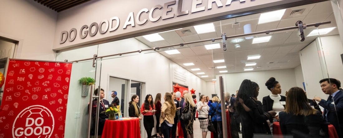 A gathering of people at the Do Good Accelerator, standing around tables and interacting with each other. 