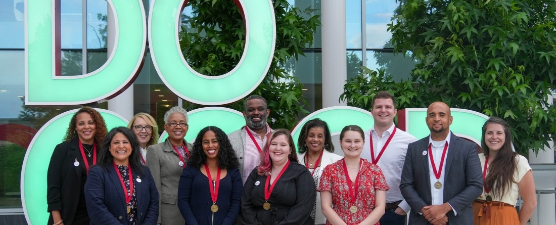 Certificate students standing in front of a do good sculpture