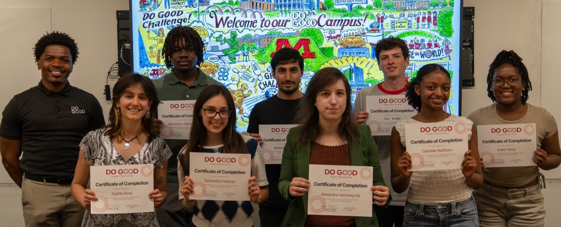 9 Students Standing up All together, holding their Impact Bootcamp Certificates
