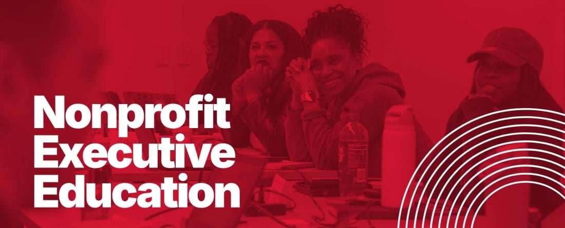 A group of people sitting at a table smiling at a presenter. The image is overlayed with a red filter and white writing that says Nonprofit Executive Education.
